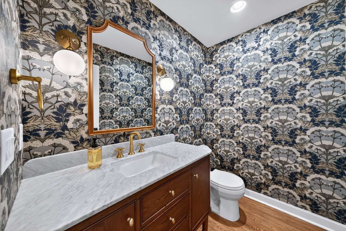 The powder room offers a luxurious feel with its upscale wallpaper and design selections.