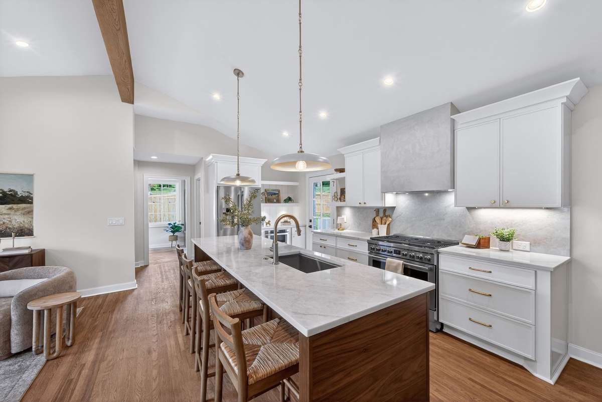 The designer kitchen features a large island with complementary walnut cabinetry and quartz surfaces.
