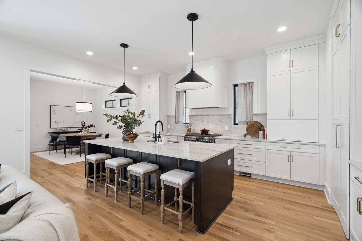 Entertain in style with an oversized island boasting custom stone countertops, a custom-made oven hood, paneled refrigerator, and hidden scullery