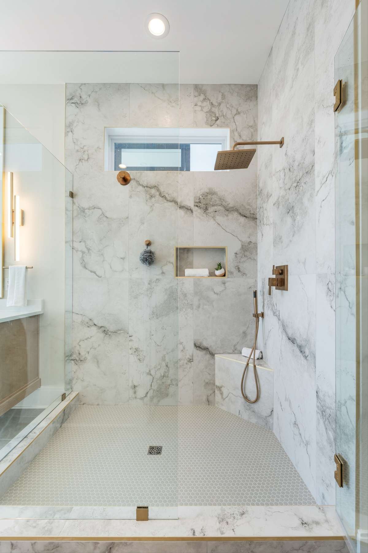Large shower with bench, niche and handheld.