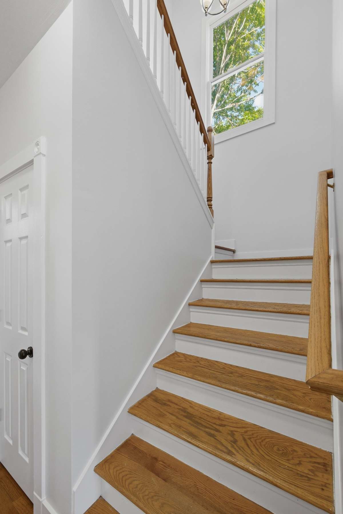 Real oak stair treads up to the second floor. The door on the left opens to a closet with good storage as well as the water heater, which was installed in 2023.