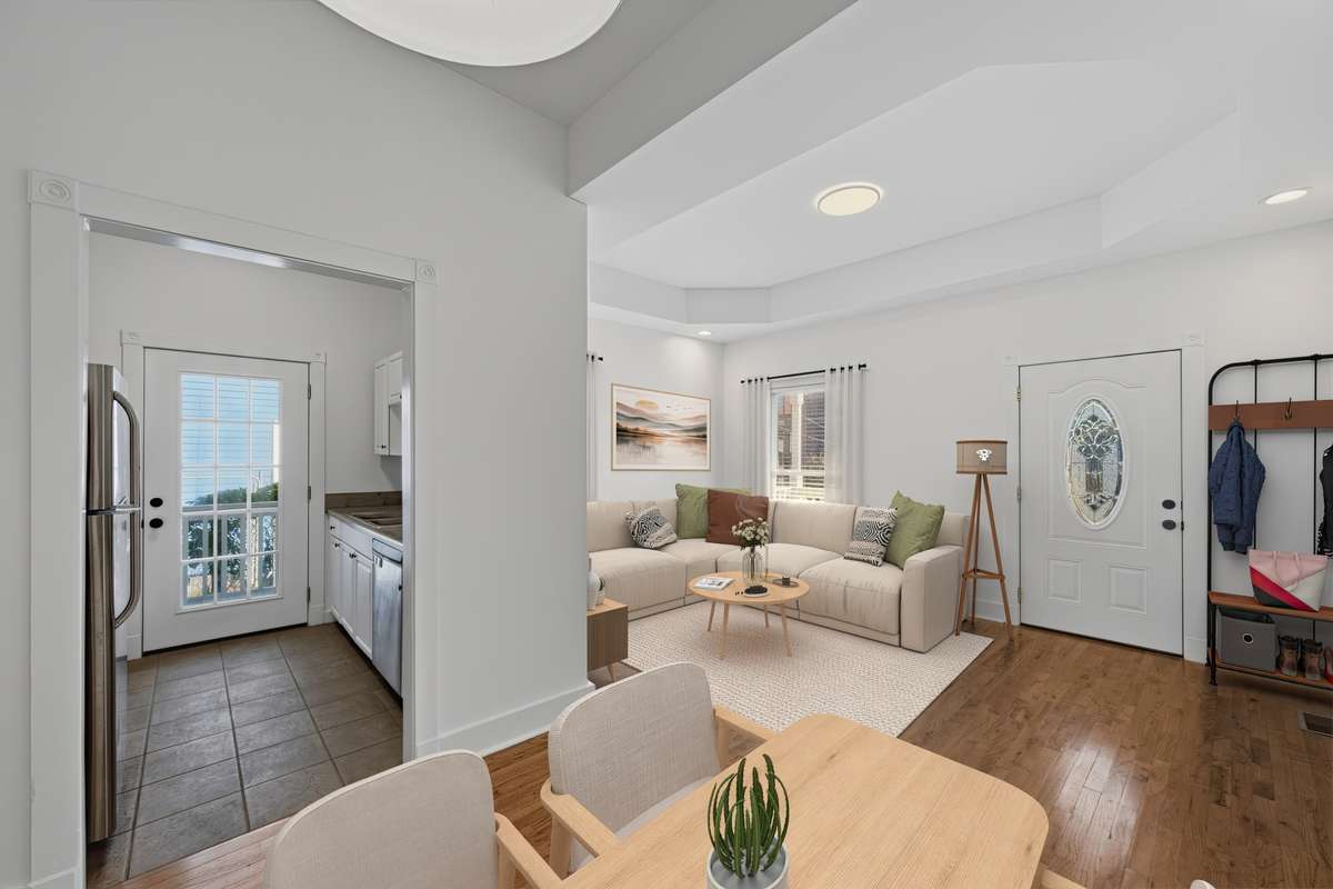 A view from the dining area looking towards the living room and into the kitchen. Virtually staged.