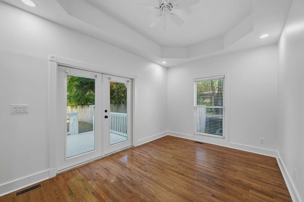 Another view of the bedroom on the main floor, which also has access to the private deck and back yard through the French doors. Notice the tray ceiling and ceiling fan as well.
