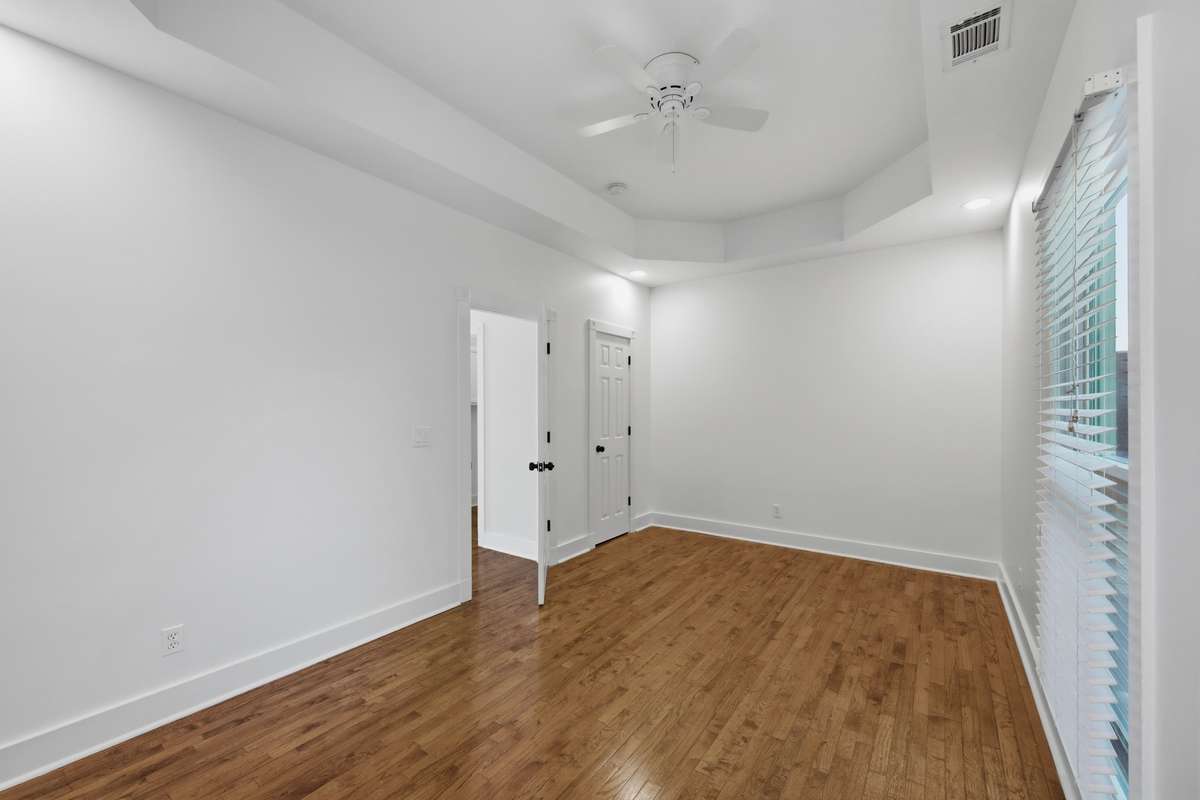 The secondary bedroom upstairs is large and also has a tray ceiling and ceiling fan. The far door opens to a closet.
