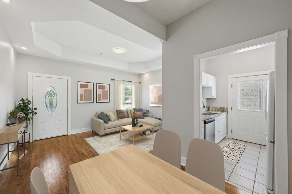 A view from the dining area looking towards the living room and into the kitchen. Virtually staged.