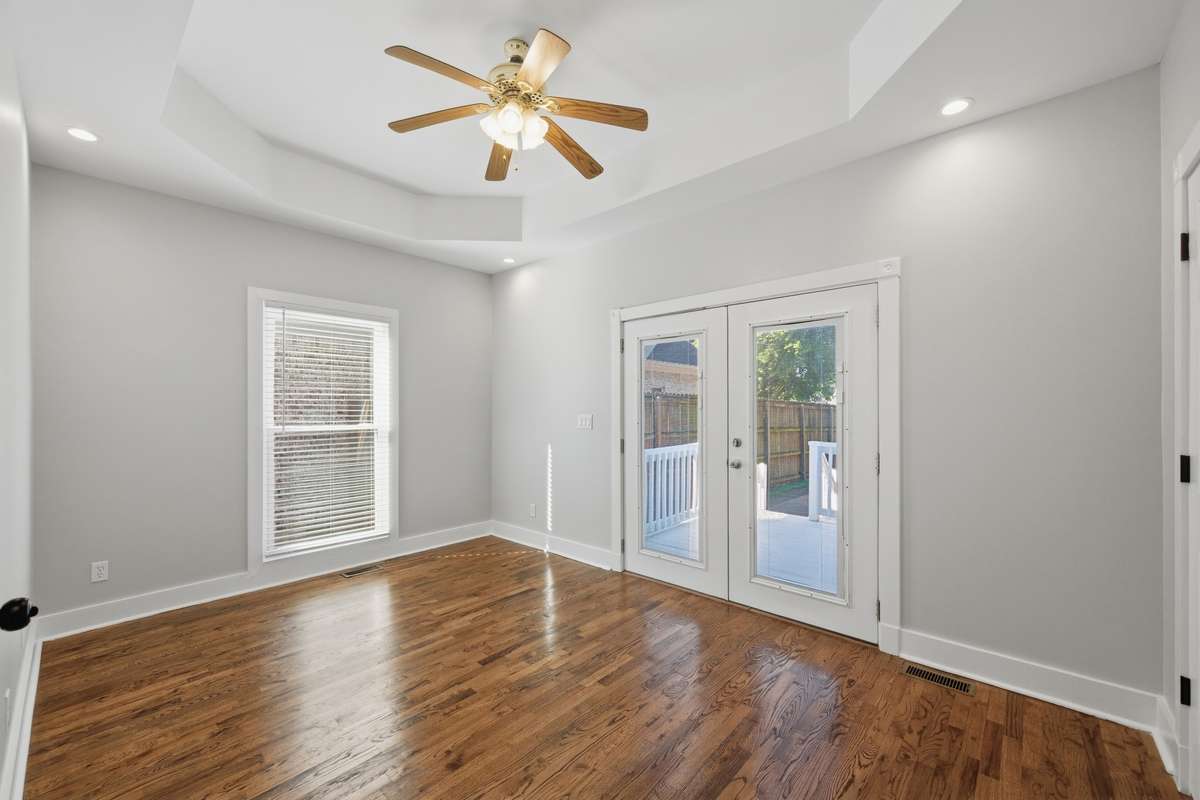 Another view of the bedroom on the main floor, which also has access to the private deck and back yard through the French doors. Notice the tray ceiling and ceiling fan as well.