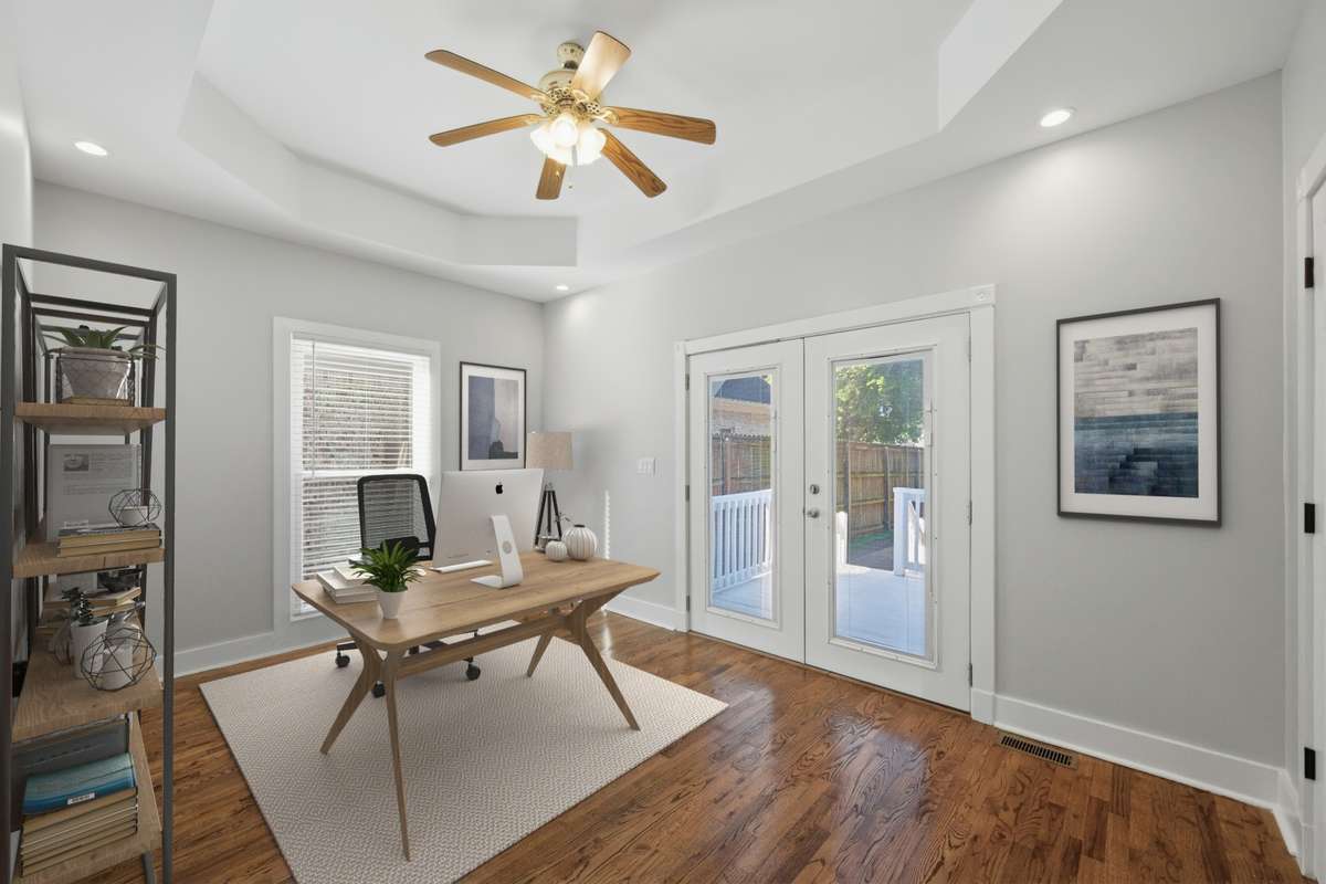Another view of the bedroom on the main floor, which also has access to the private deck and back yard through the French doors. Notice the tray ceiling and ceiling fan as well. Virtually staged.