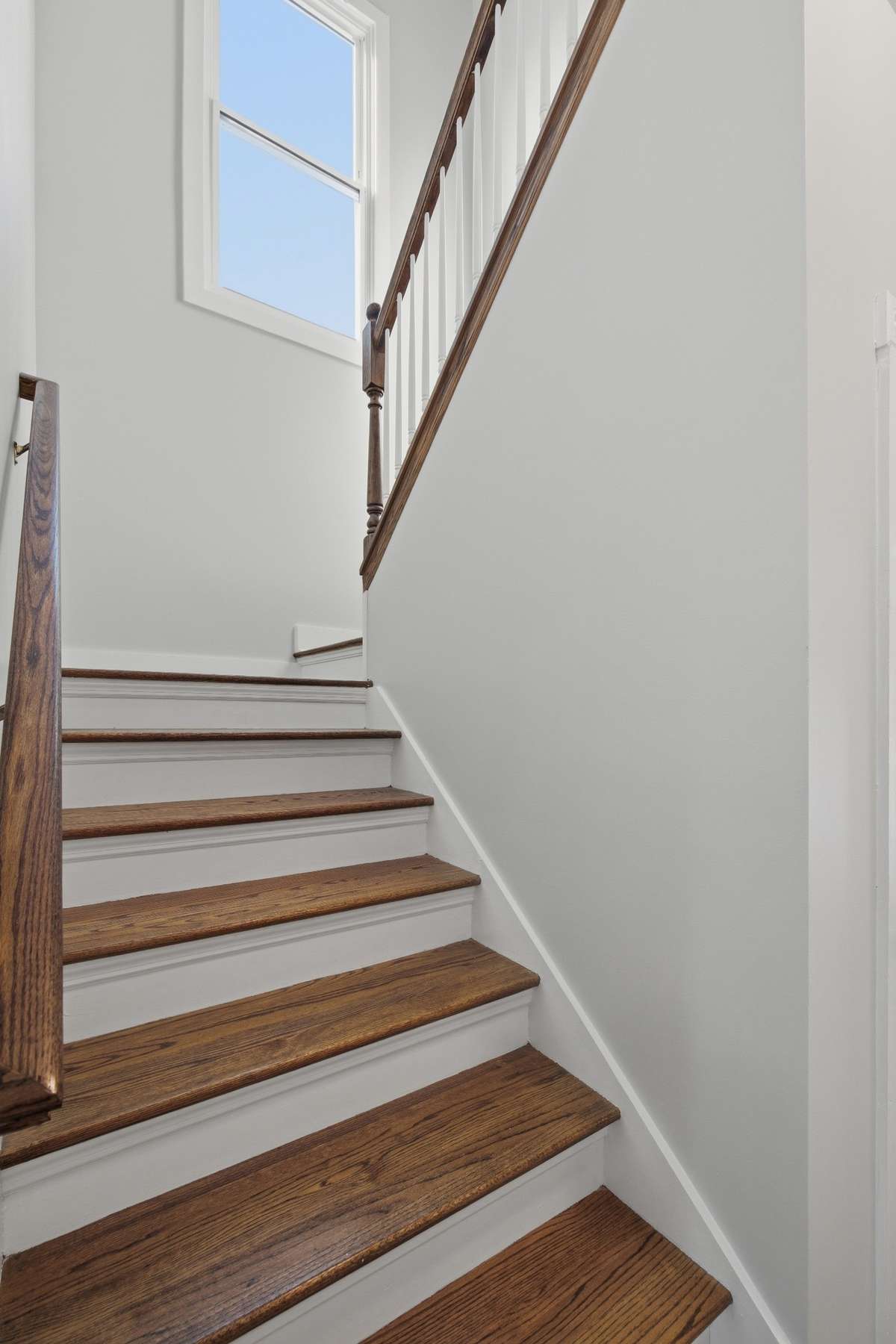 Real oak stair treads up to the second floor. There is a door out of frame to the right that opens to a storage closet.