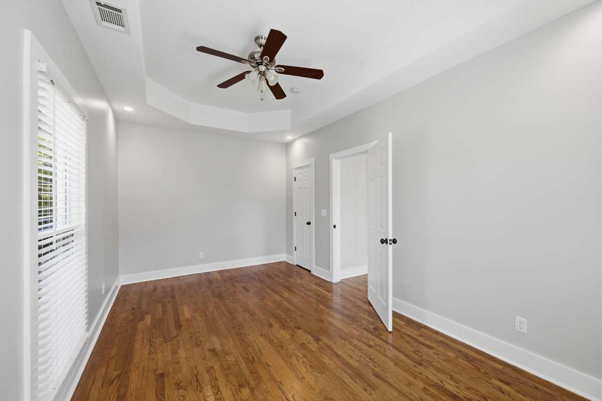 The secondary bedroom upstairs is large and also has a tray ceiling and ceiling fan. The far door opens to a closet.