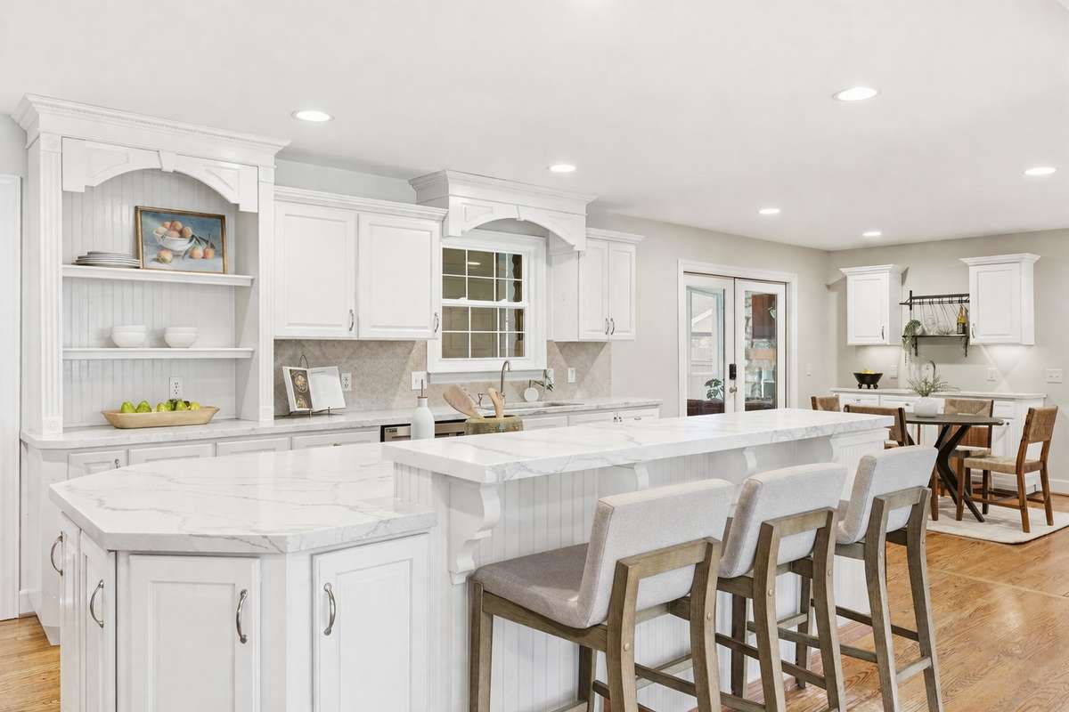 virtually edited. This kitchen has a fabulous layout and could easily be renovated with painted cabinets and new countertops. The floorplan is open and spacious, and the kitchen opens to the screened porch.