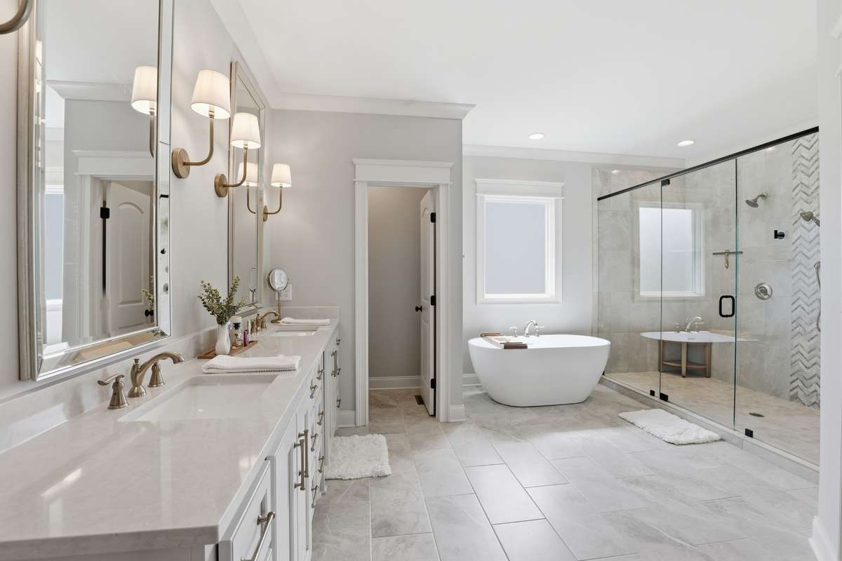 Pure elegant primary en suite with double vanities and sconce lighting
