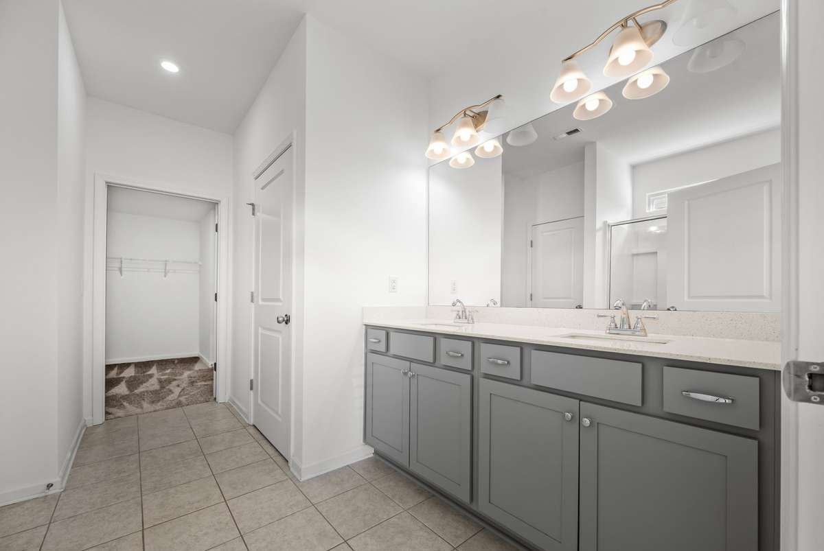 This spacious primary bath feels bright and calming, with double sinks and a clean, modern design. The connected walk‑in closet adds easy everyday convenience, creating a relaxing retreat that keeps life beautifully organized.