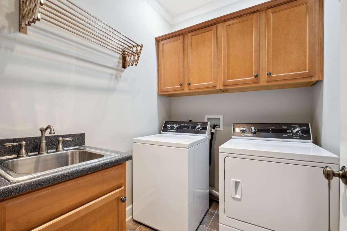 The laundry room has ample cabinets, utility sink and drying rack. The washer and dryer do not remain.