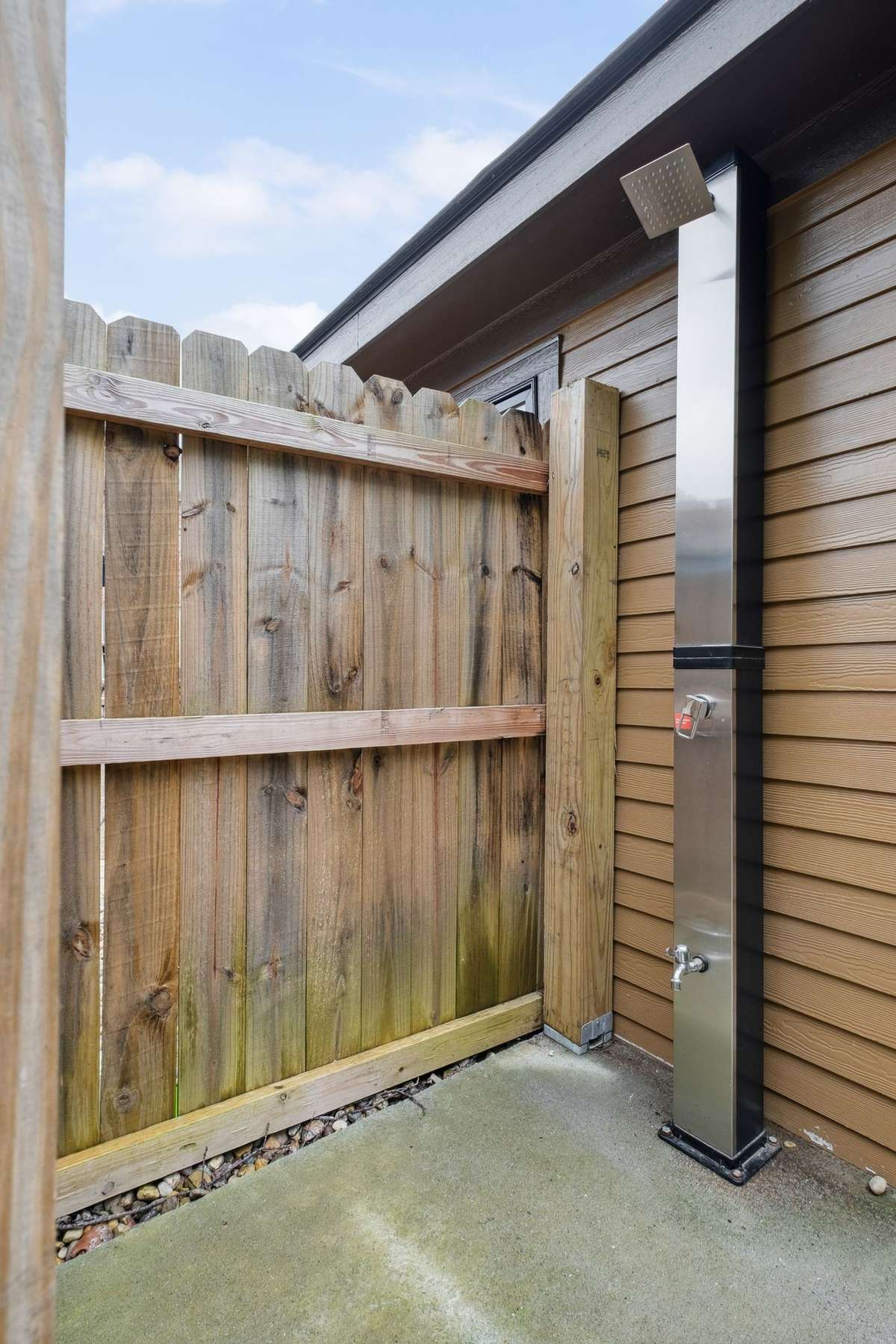 Adjacent to the pool house is an outdoor shower overlooking the back tree line.