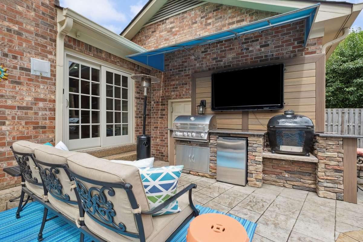 Grilling is a breeze in the outdoor kitchen with granite countertops, bar seating, gas grill, refrigerator, and space for a charcoal grill (green egg does not remain). An awning provides protection from the elements.