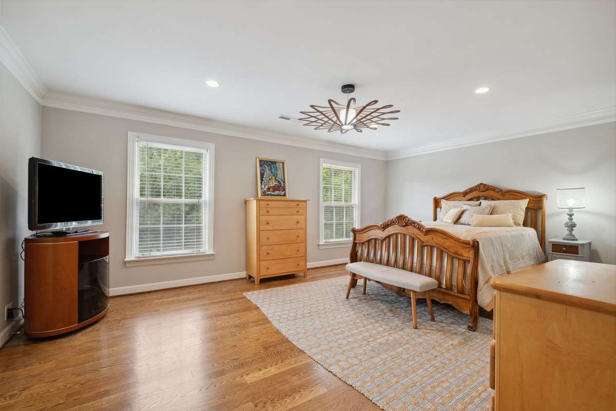 The spacious primary suite has great natural light and overlooks the pool and tree line beyond.