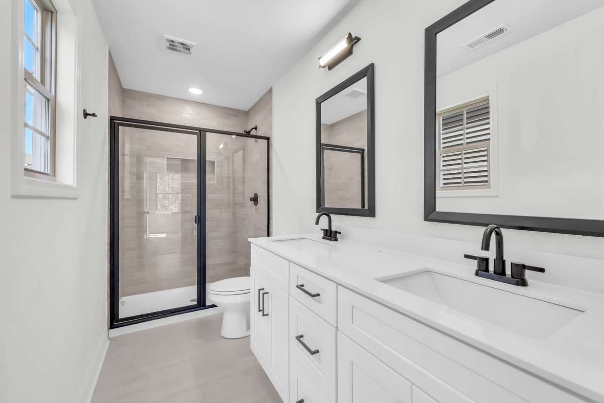 Dual vanities in the master suite, tile flooring and tile shower with oil rubbed bronze framed glass door