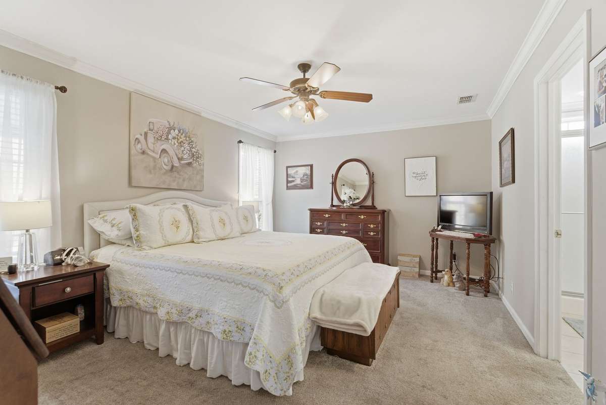 Primary bedroom features two windows, crown molding.