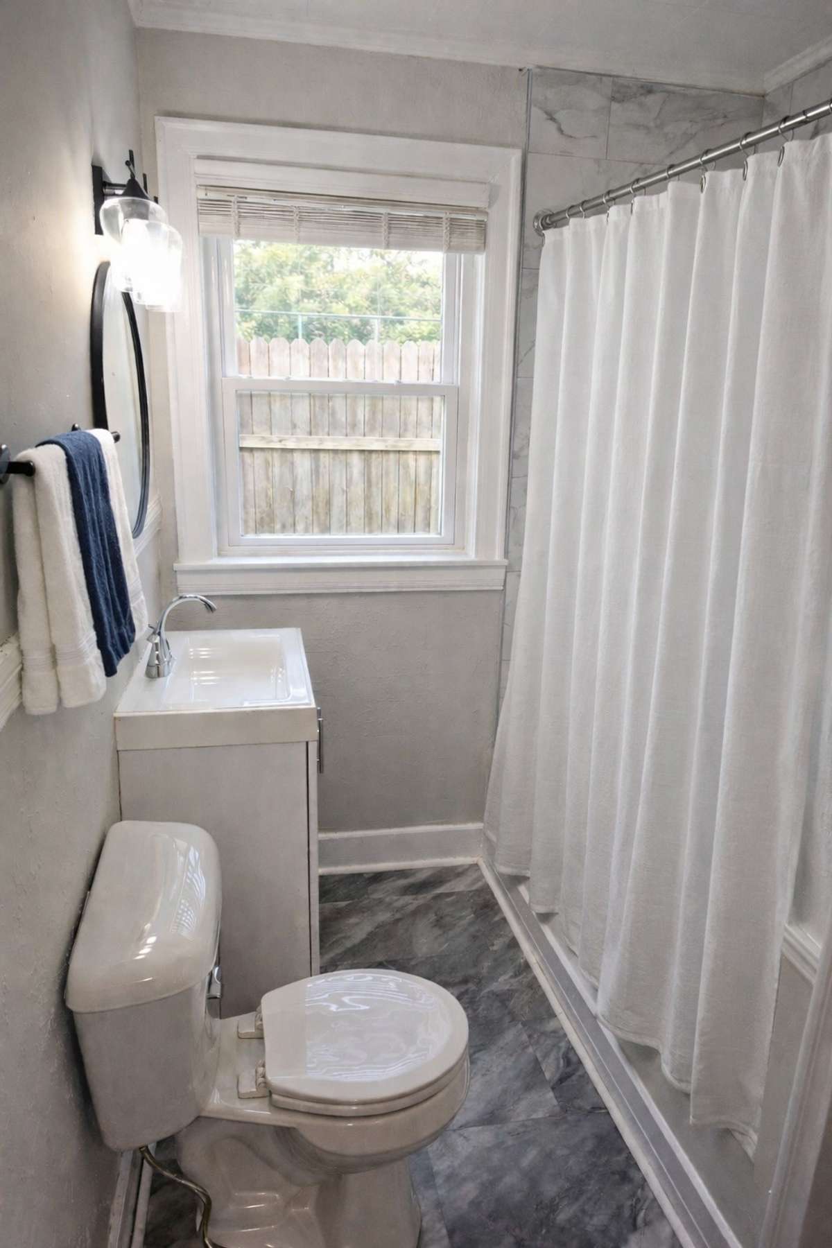Unit B bathroom updated with new tile shower surround and new flooring in 2025. Virtually staged.