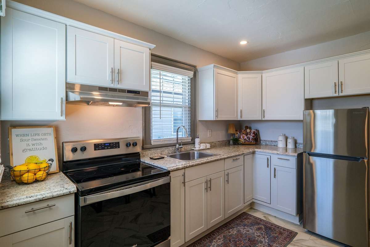 Unit A: Stainless steel oven and refrigerator, large single-bowl sink with pull-down sprayer faucet, and plenty of storage. Photo from 2021.