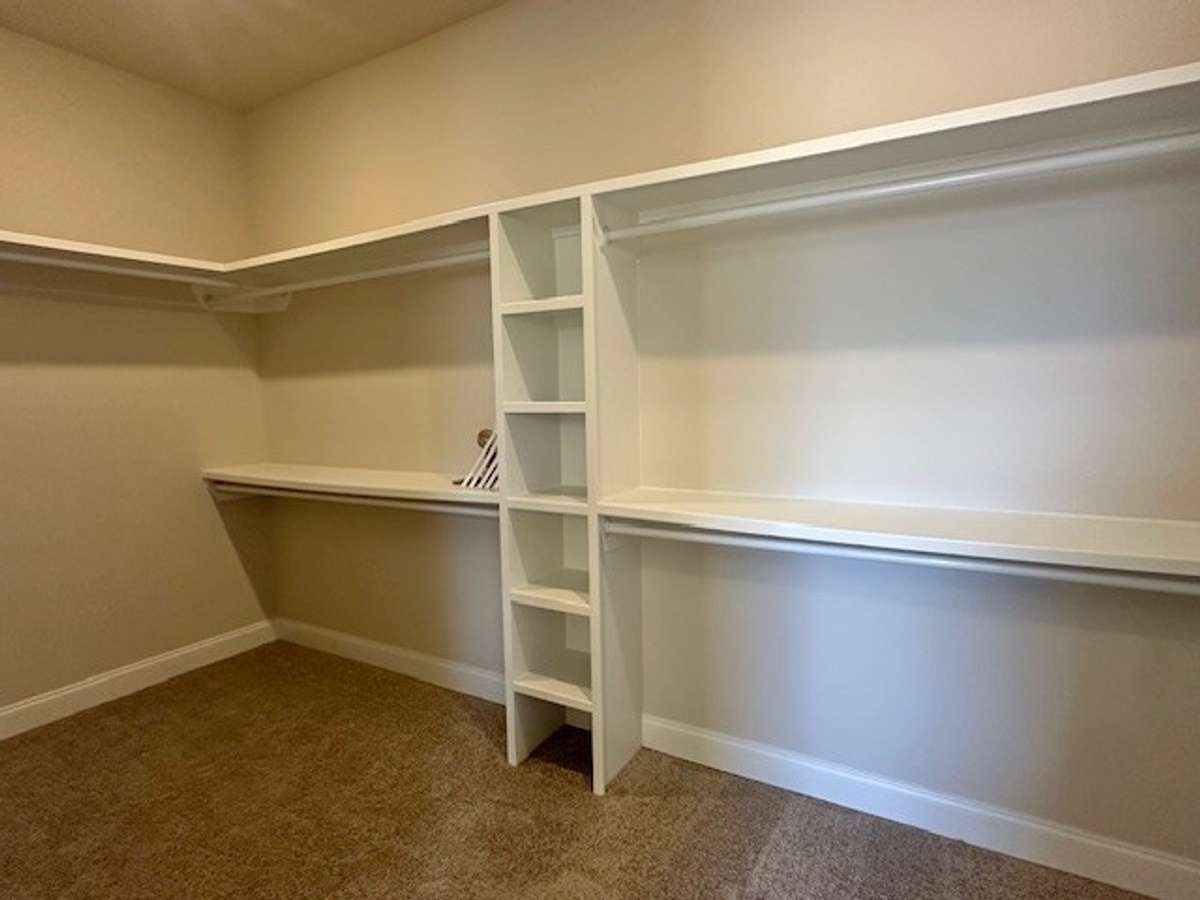 Custom wood shelving in the oversized primary walk in closet makes organization a dream!