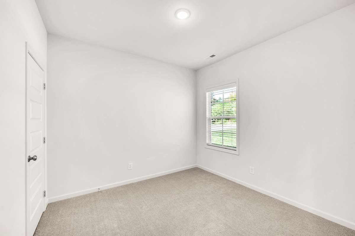 Comfortable secondary bedroom with neutral tones, plush carpet, and a large closet.