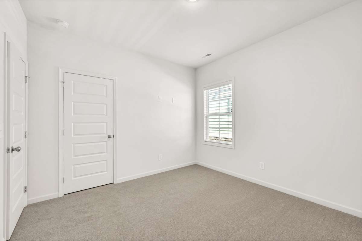 Bright and inviting secondary bedroom with soft carpeting and natural light.
