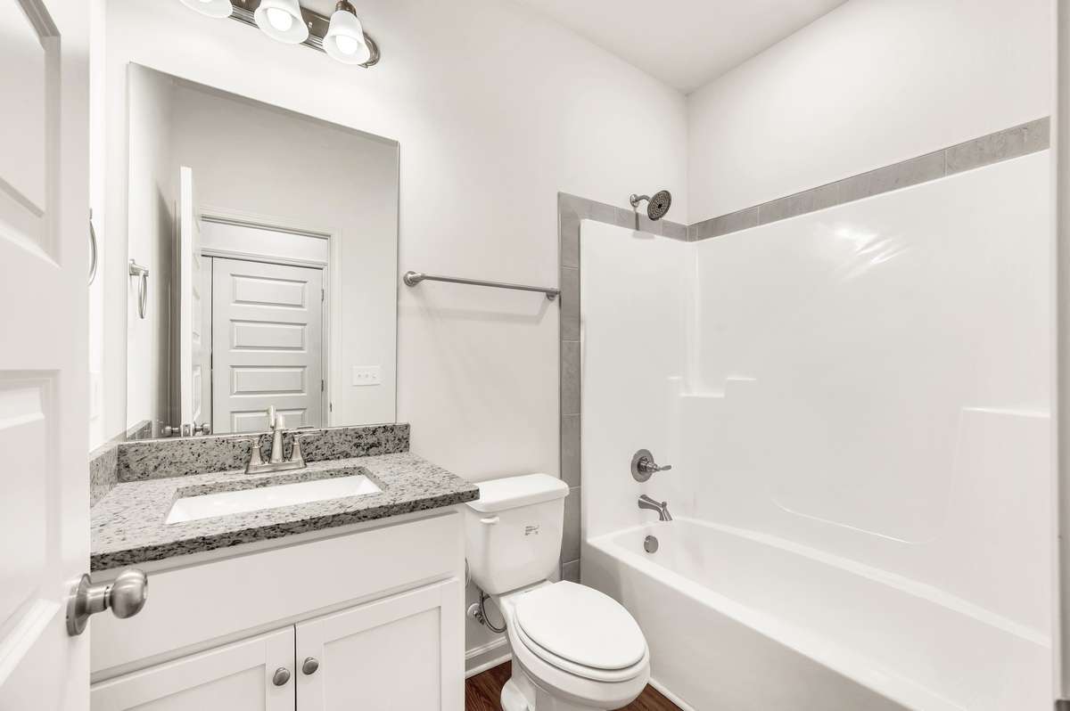 Bright secondary bath featuring a granite vanity, brushed nickel fixtures, and a clean tile-accent surround—fresh, functional, and ready for everyday living.