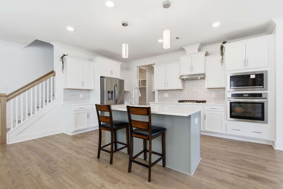 Gourmet kitchen showcasing a gas cooktop, subway tile backsplash, built-in ovens, and ample prep space.
