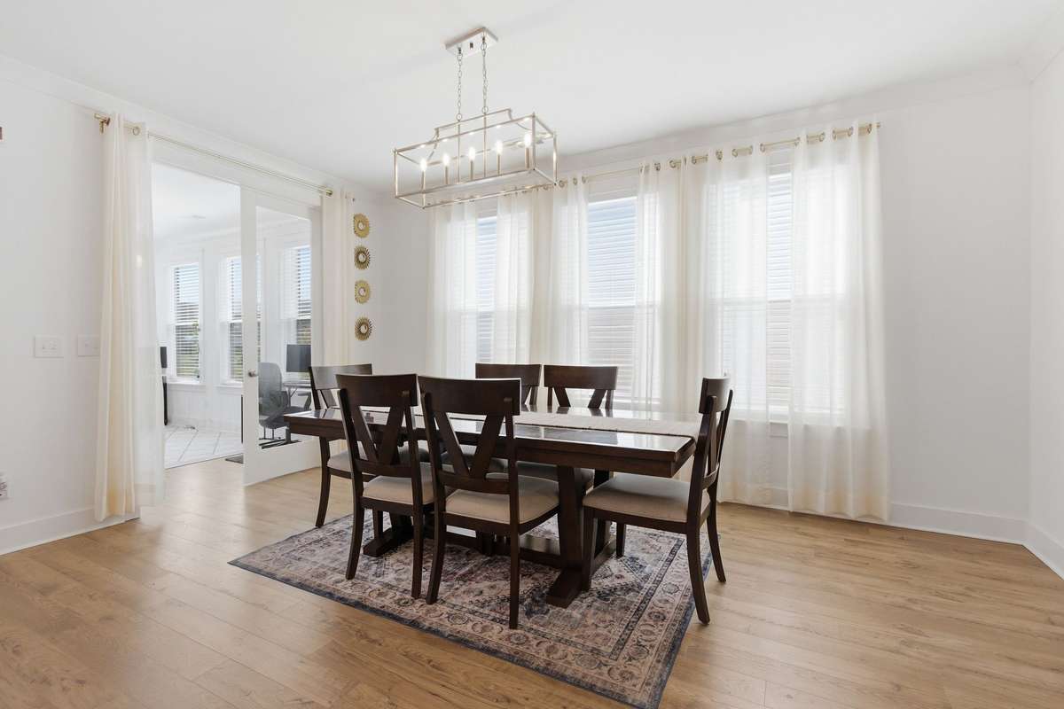 Dining area featuring a modern chandelier and natural light from the adjoining sunroom.