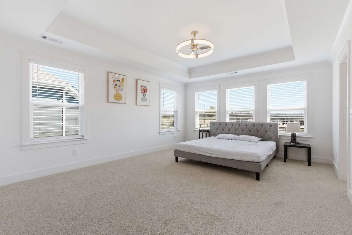 Luxurious primary bedroom suite featuring a stunning tray ceiling and modern ceiling fan.
