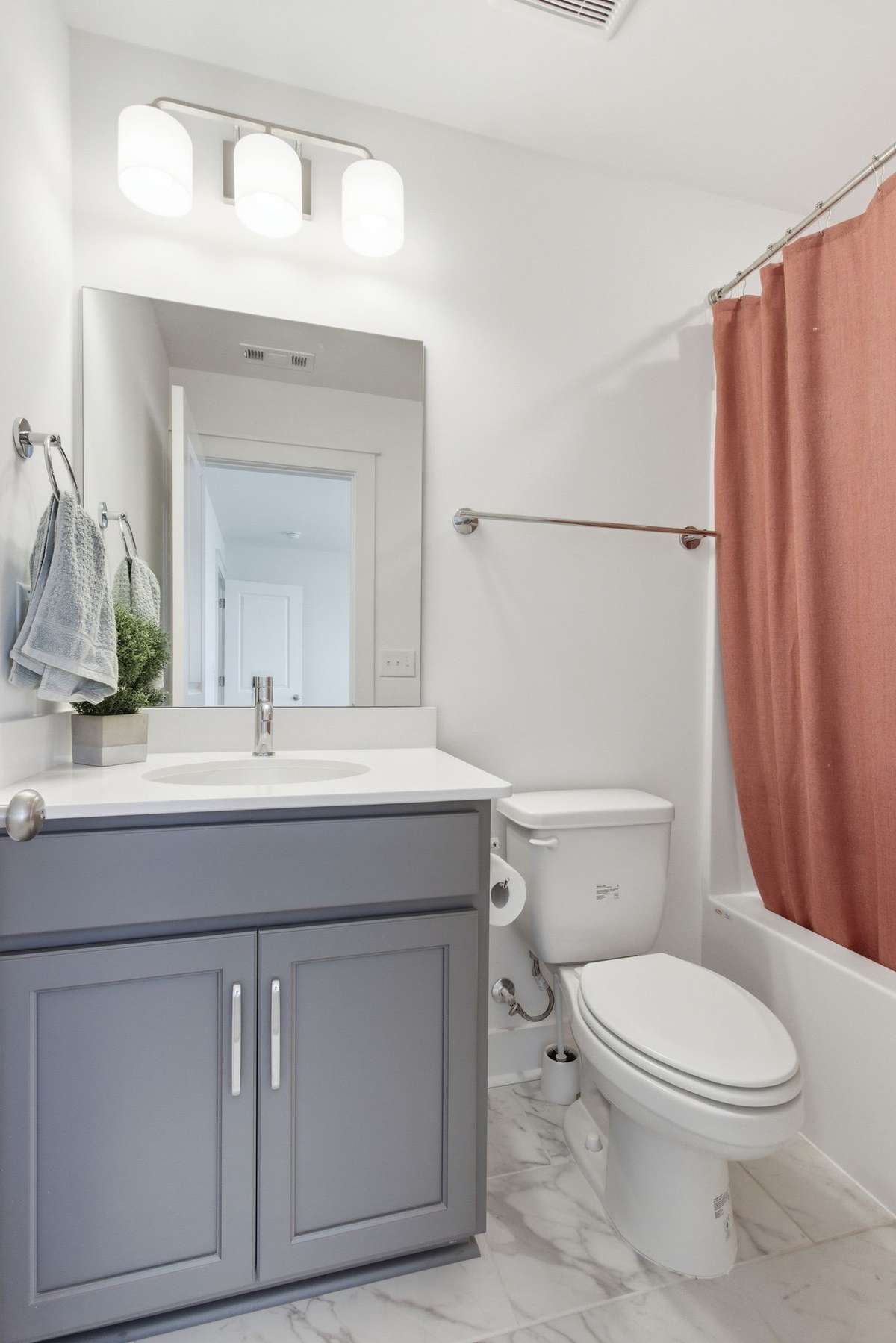 Upstairs full bathroom featuring a modern gray vanity and shower/tub combo.