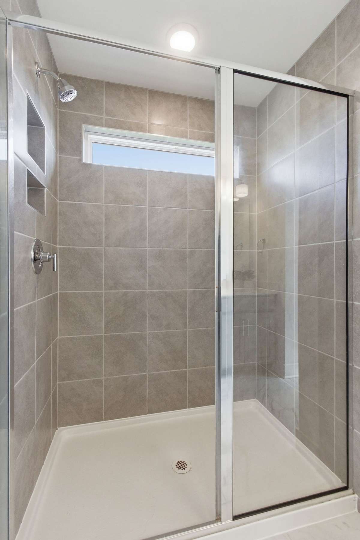 Primary bathroom featuring a glass-enclosed, beautifully tiled walk-in shower.