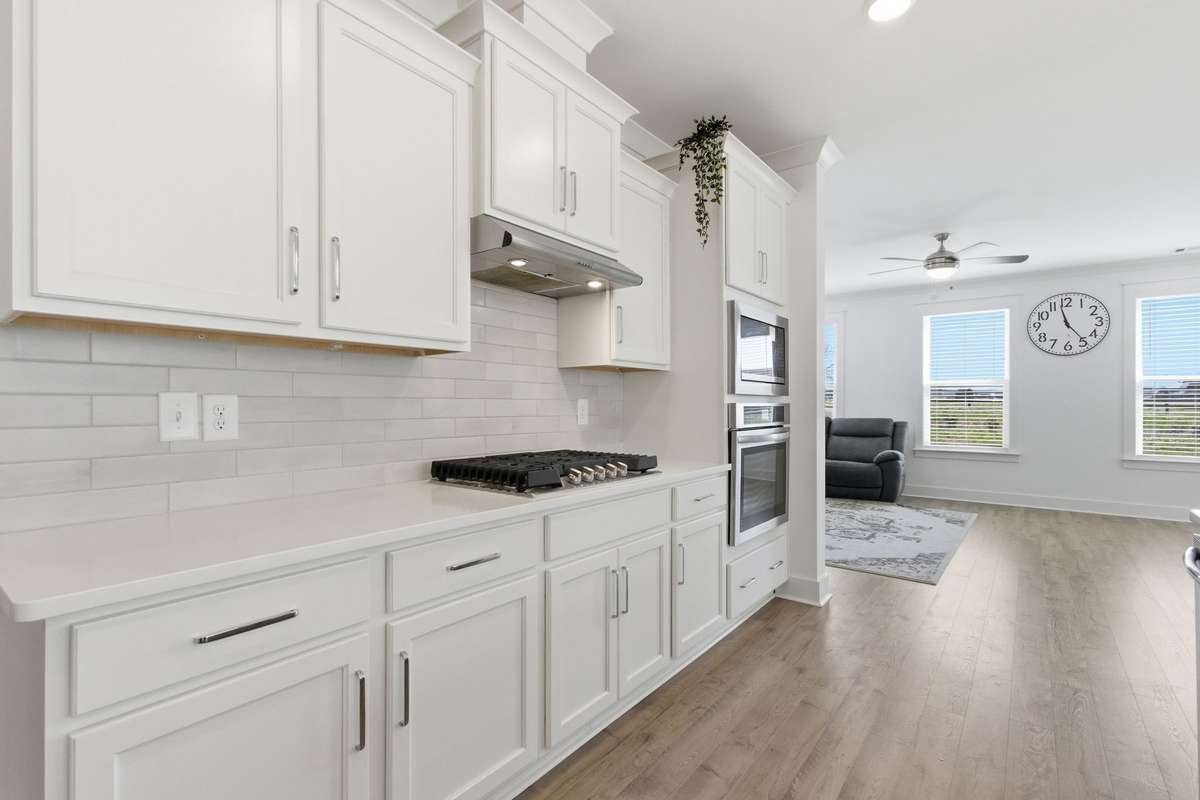 Gourmet kitchen showcasing a gas cooktop, subway tile backsplash, built-in ovens, and ample prep space.