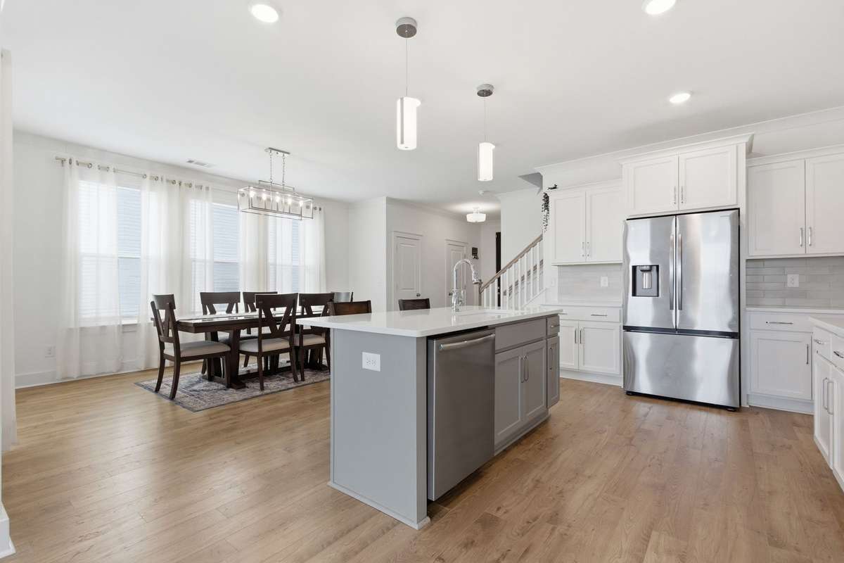 View of the kitchen island highlighting the stainless steel dishwasher, sink, and refrigerator.