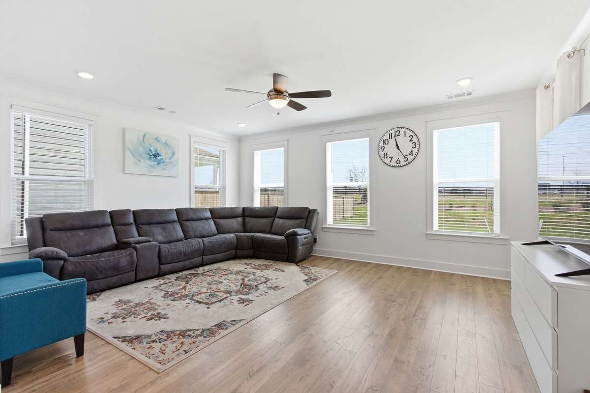 Spacious, light-filled living room area with a ceiling fan.