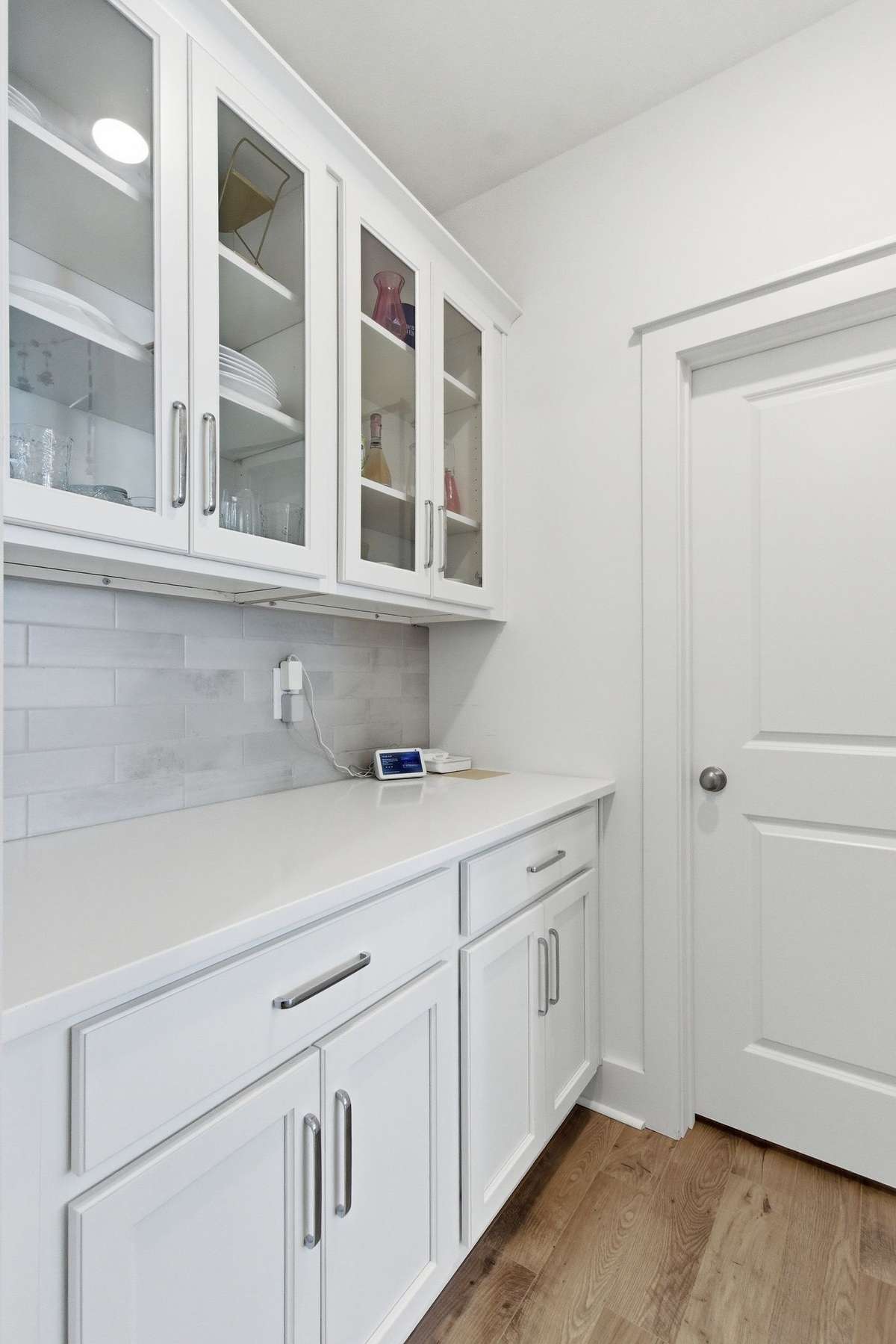 Sophisticated butler's pantry with glass-front upper cabinets and quartz countertops.