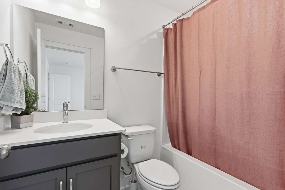 Upstairs full bathroom featuring a modern gray vanity and shower/tub combo.