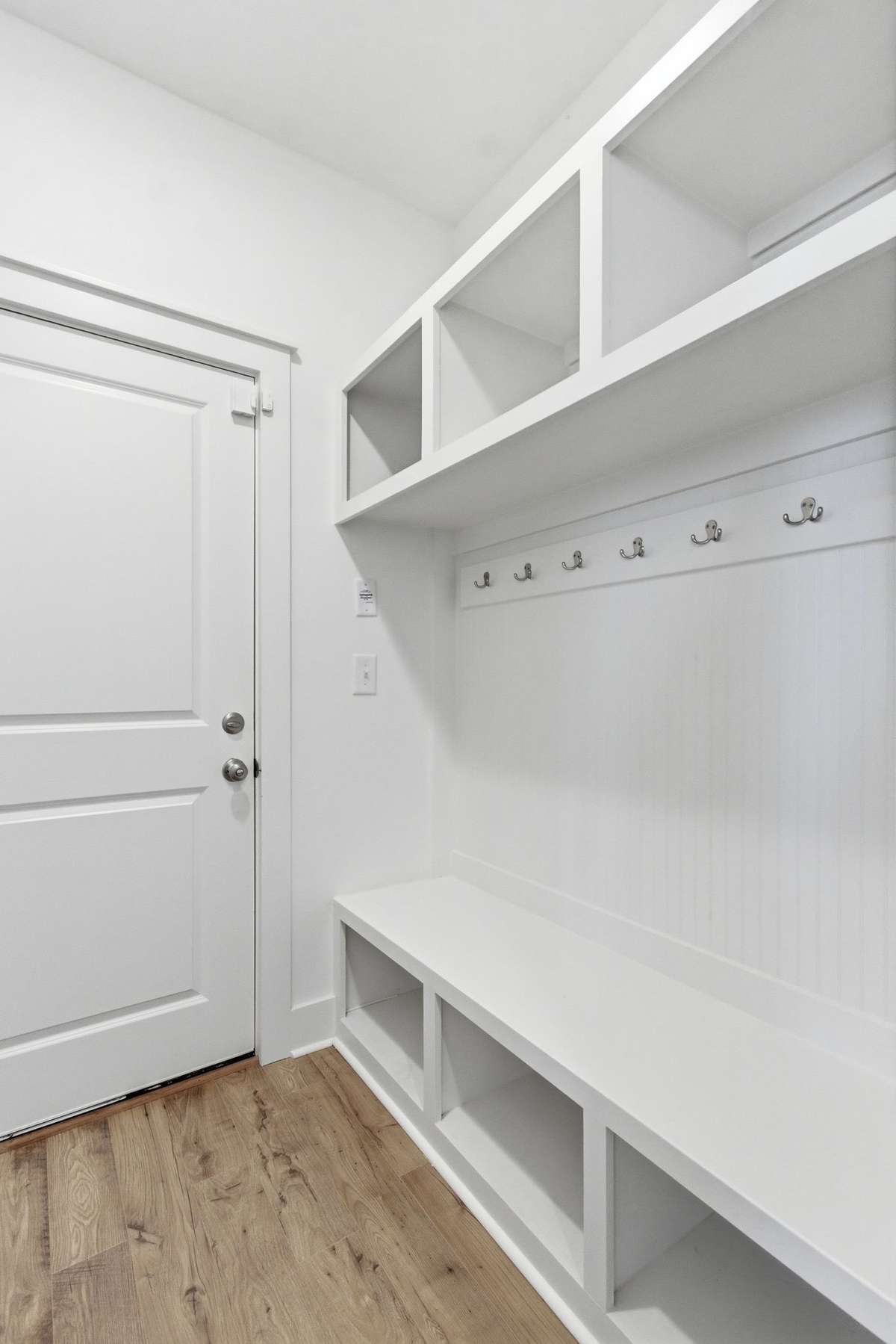 Highly functional custom mudroom drop-zone with built-in cubbies and hooks near the garage entry.
