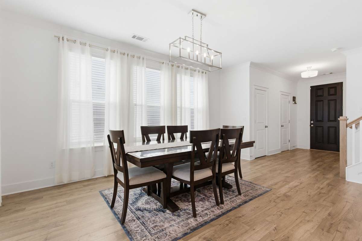 Dining area featuring a modern chandelier and natural light from the adjoining sunroom.