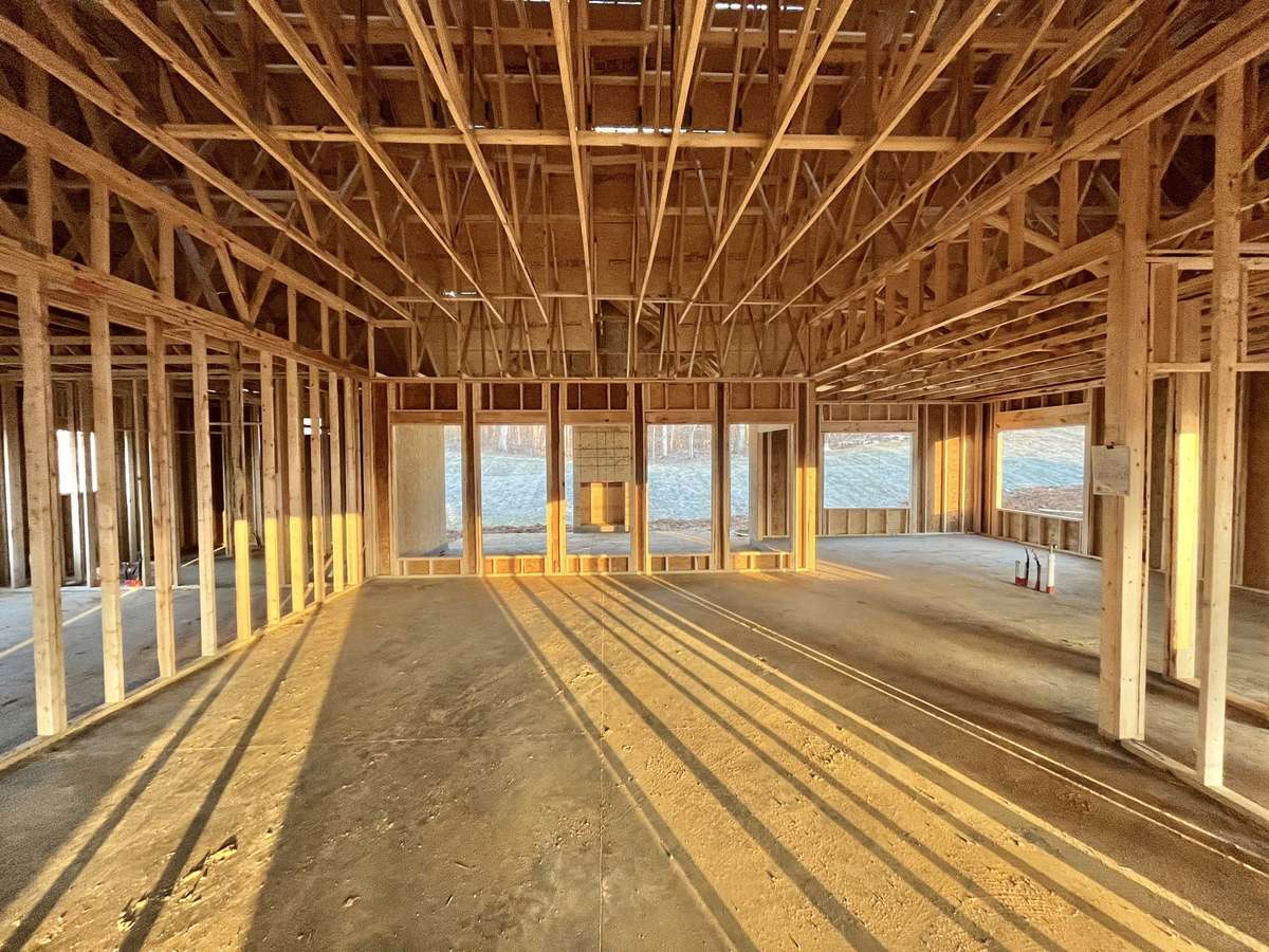 Stock photo of Great room. 11.5 ft high ceilings. Kitchen with large island and dining area are off to the back right corner in front of two large windows.