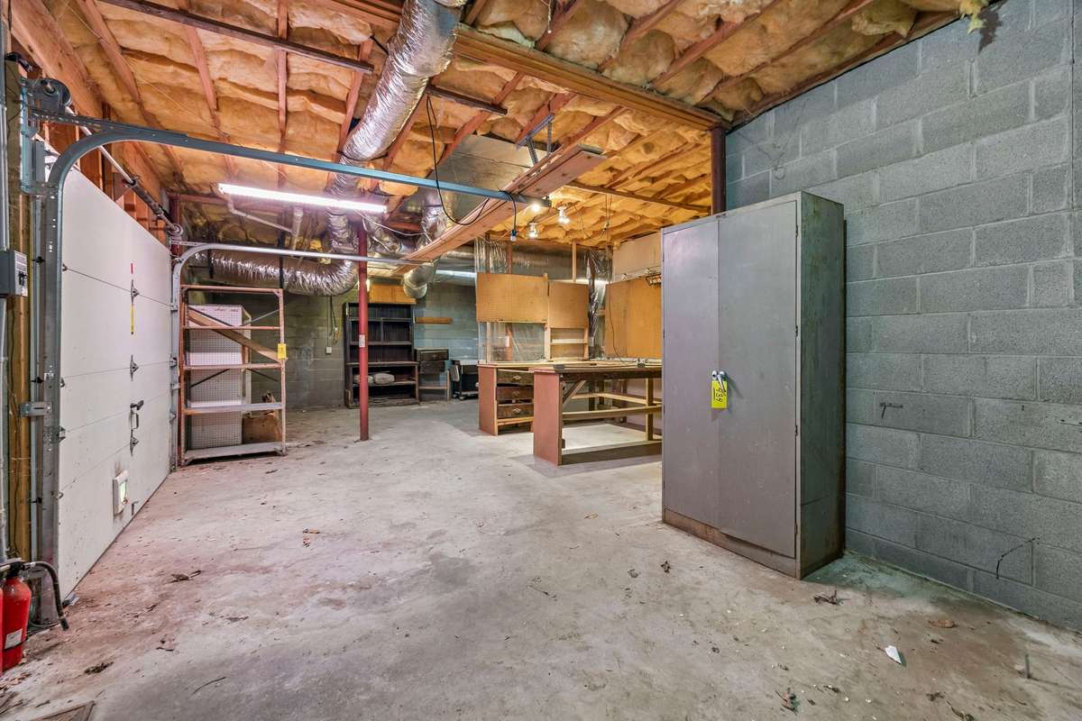 Rest of unfinished basement space with garage door. Lots of built in shelving that remains with the house.