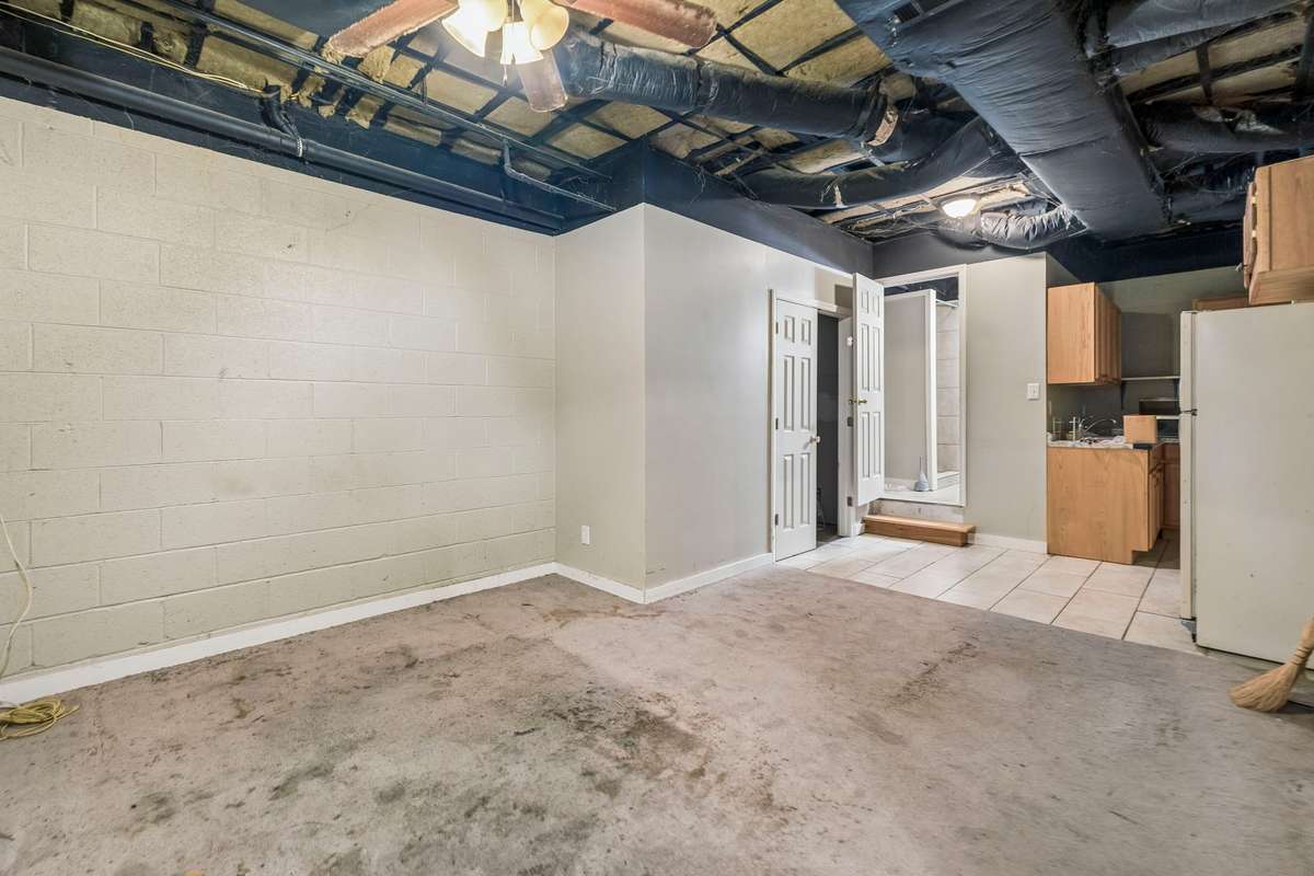 Third finished area of the basement.  The ceiling has not been enclosed but there is a 3/4 bath in this room, as well as a kitchenette.