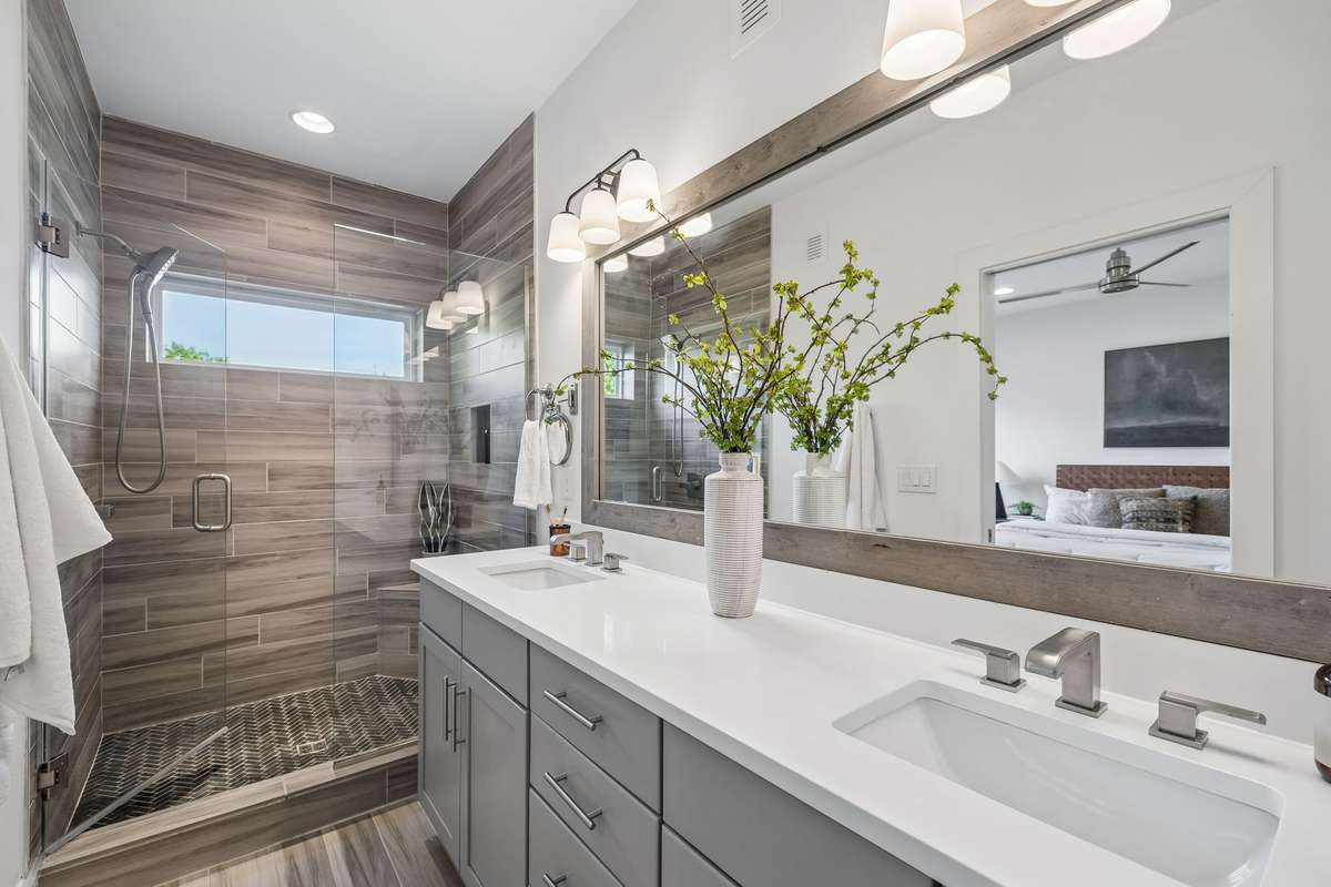 The private bath features quartz vanities framed by an extra-wide mirror and updated lighting.