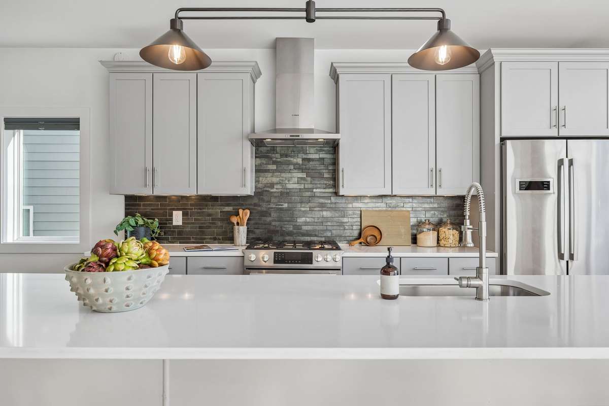 A chic new chandelier illuminates the wide quartz island.