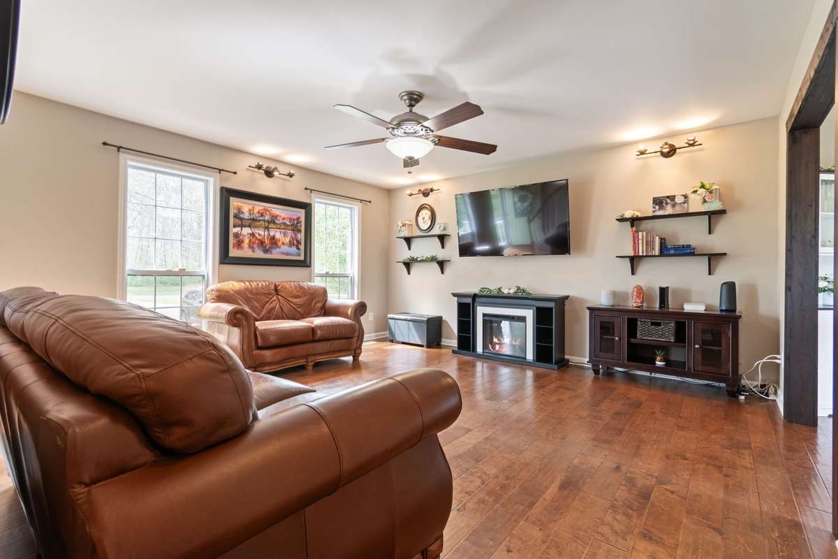 Natural light fills the living area through multiple windows looking out into the rolling front lawn, creating an airy space for everyday living and entertaining.