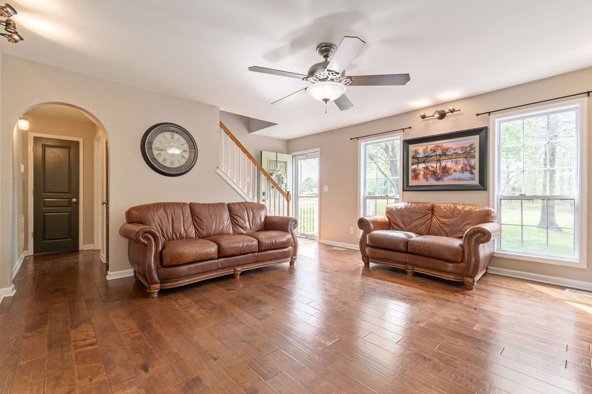 Warm hardwood floors, a modern ceiling fan, and big windows create an inviting space to relax or entertain.
