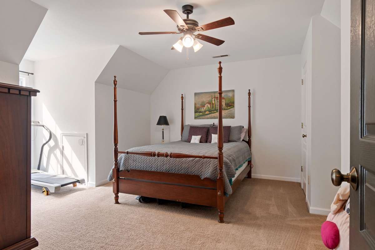 This inviting bedroom features soft carpet, a ceiling fan, and a calm, relaxing feel at the end of the day.