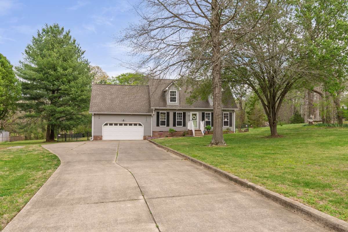 A wide driveway leads to the home and attached garage, creating a welcoming first impression with plenty of parking.