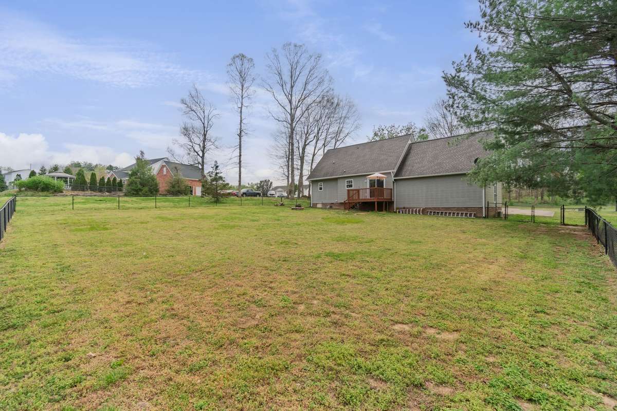 This corner view emphasizes the fenced yard and tree line, creating an ideal space for pets, games, and gatherings.